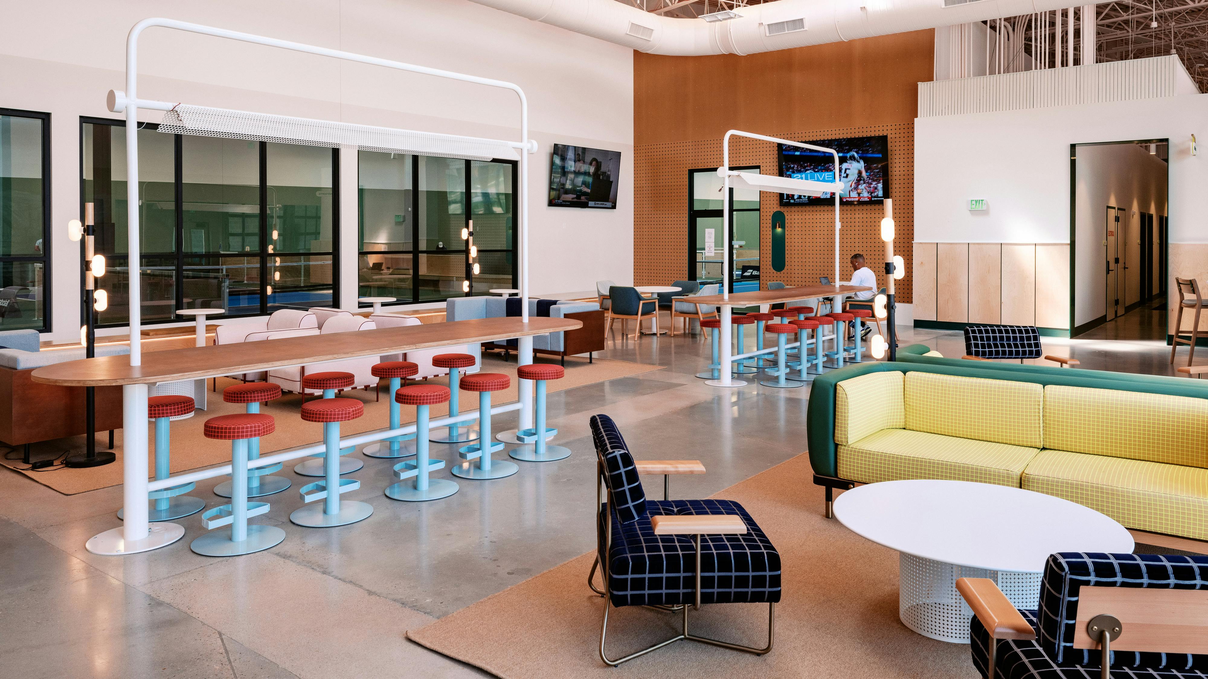 Interior food hall with fixed barstool seating at countertops, and adjacent tables and soft seating