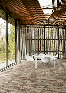 Commercial workspace with white table and bucket chairs, wood-look acoustic ceiling, and horizontal patterned carpet tile in shades of autumn leaves Commercial workspace with white table and bucket chairs, wood-look acoustic ceiling, and horizontal patterned carpet tile in shades of autumn leaves