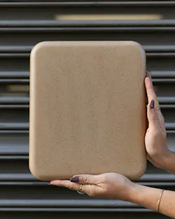 Hands holding a bio-based, speckled tan floor tile with rounded edges Hands holding a bio-based, speckled tan floor tile with rounded edges