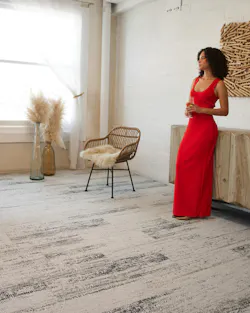 Woman in a red dress standing in a neutral-themed room on carpeted floor with gradient pattern in taupe and deep brown Woman in a red dress standing in a neutral-themed room on carpeted floor with gradient pattern in taupe and deep brown