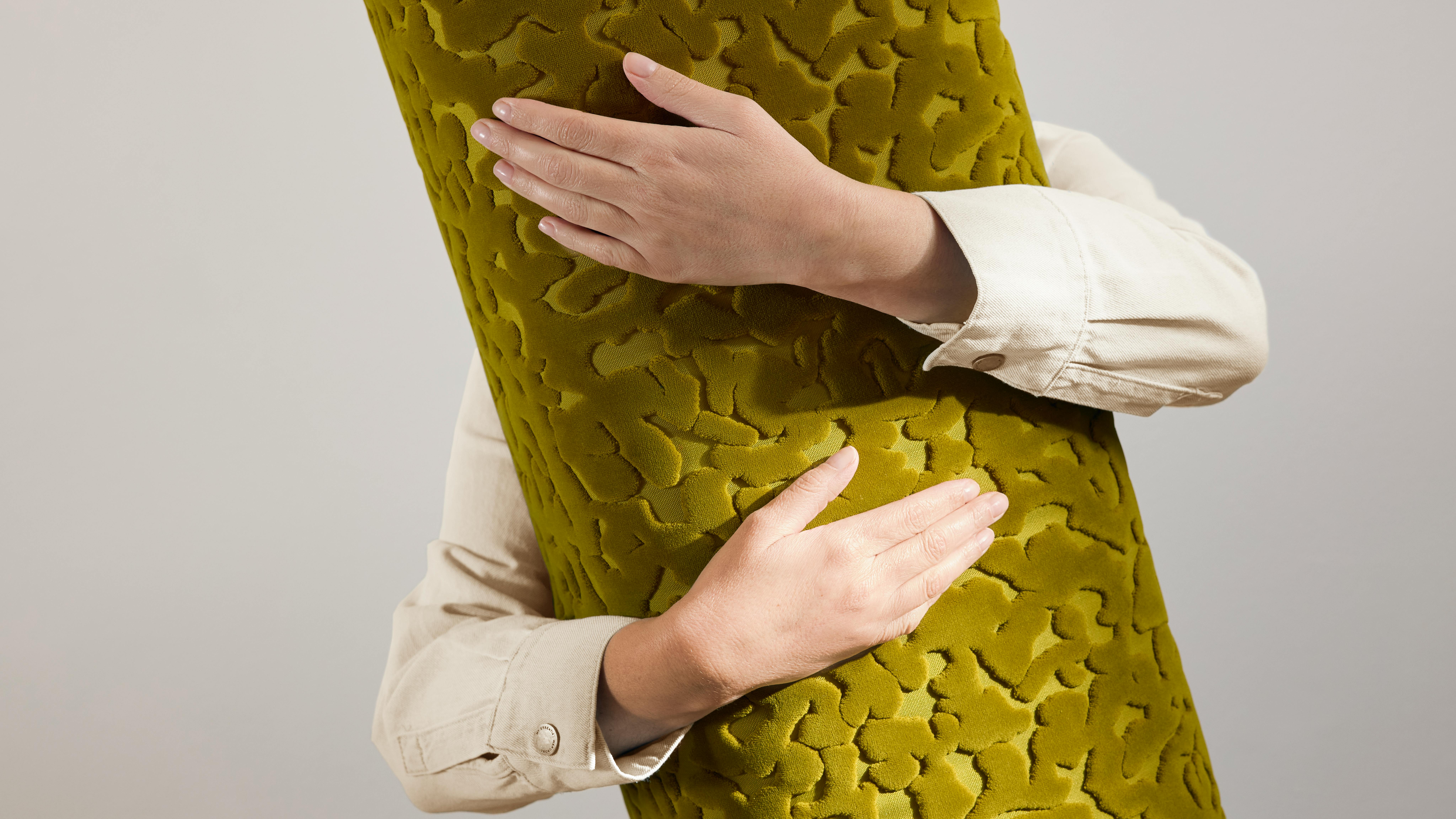 Person holding a large bolt of raised texture fabric in antique gold