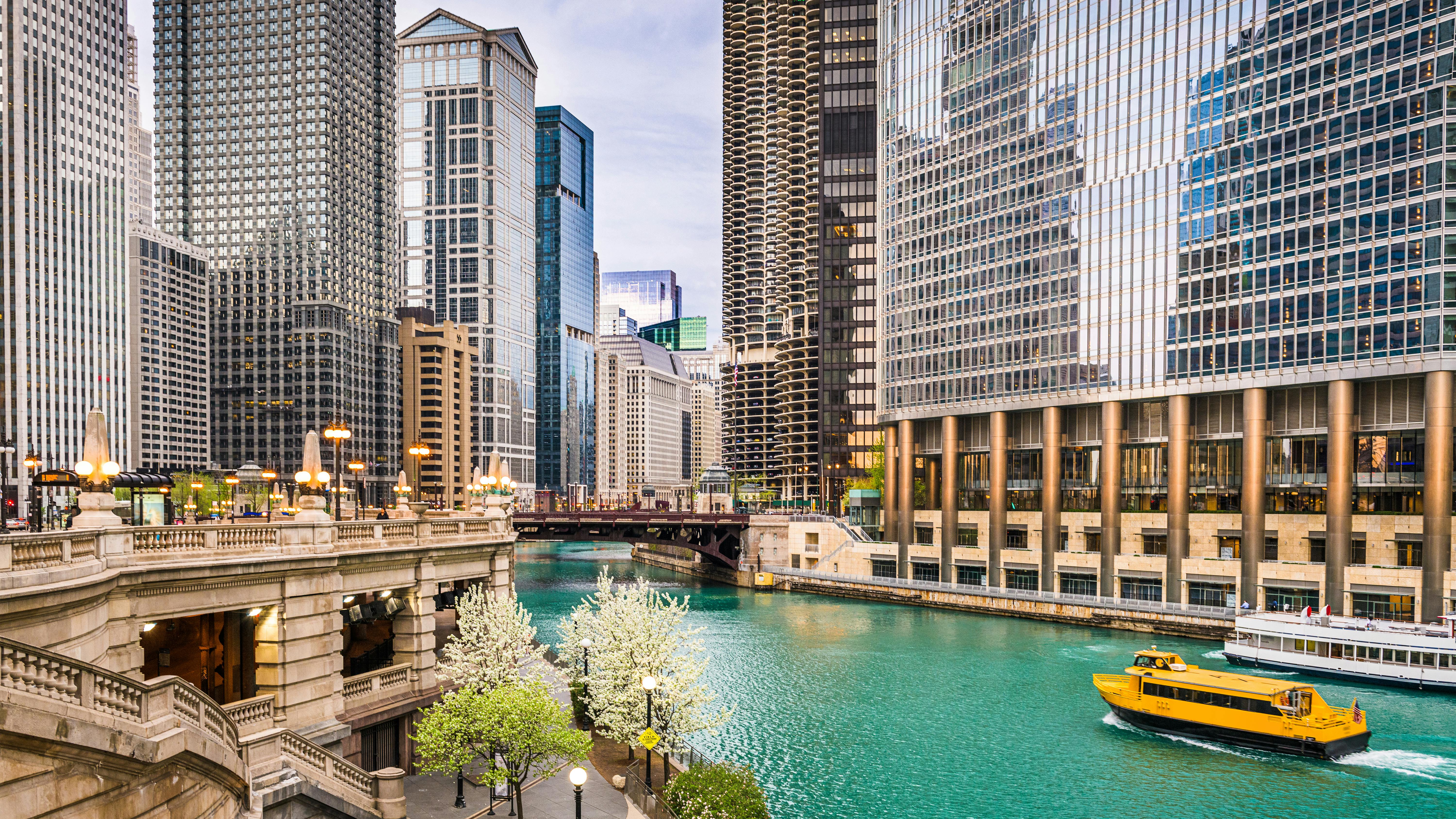 The Chicago River in downtown Chicago, Illinois. A boat cruises down the river between the tall skyscrapers.