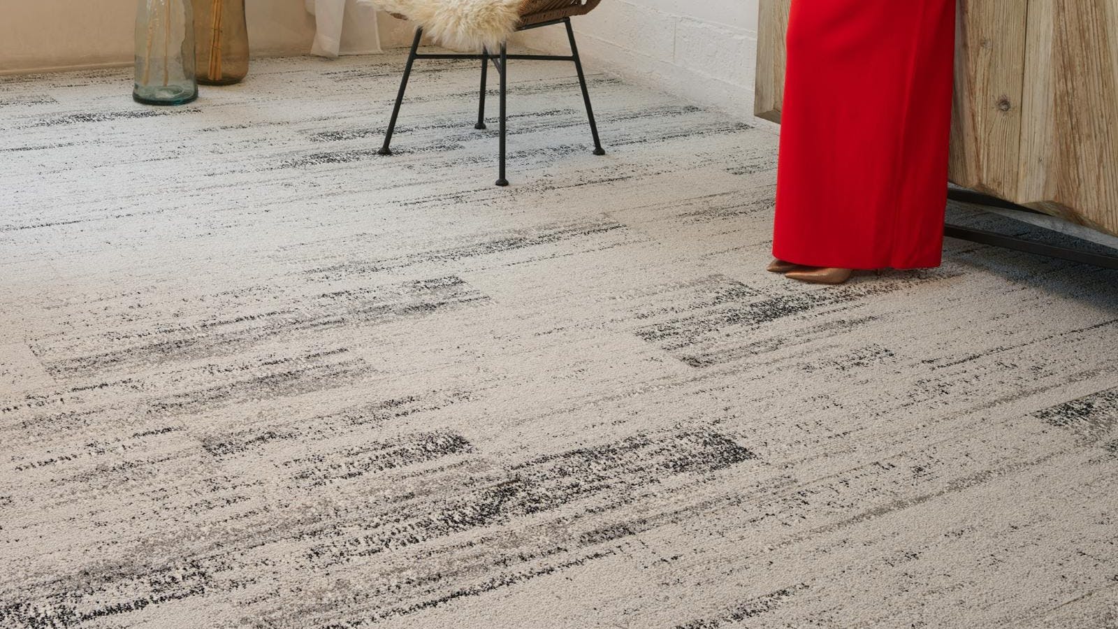 Woman in a red dress standing in a neutral-themed room on carpeted floor with gradient pattern in taupe and deep brown