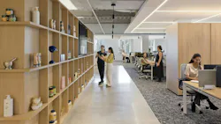 A view of the flexible work zones shows products on neutral wood shelving and adjoining workstations. A view of the flexible work zones shows products on neutral wood shelving and adjoining workstations.