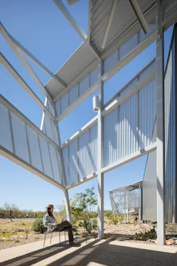 A shaded outdoor patio uses steel screens to filter daylight and allow for outdoor reading and gathering