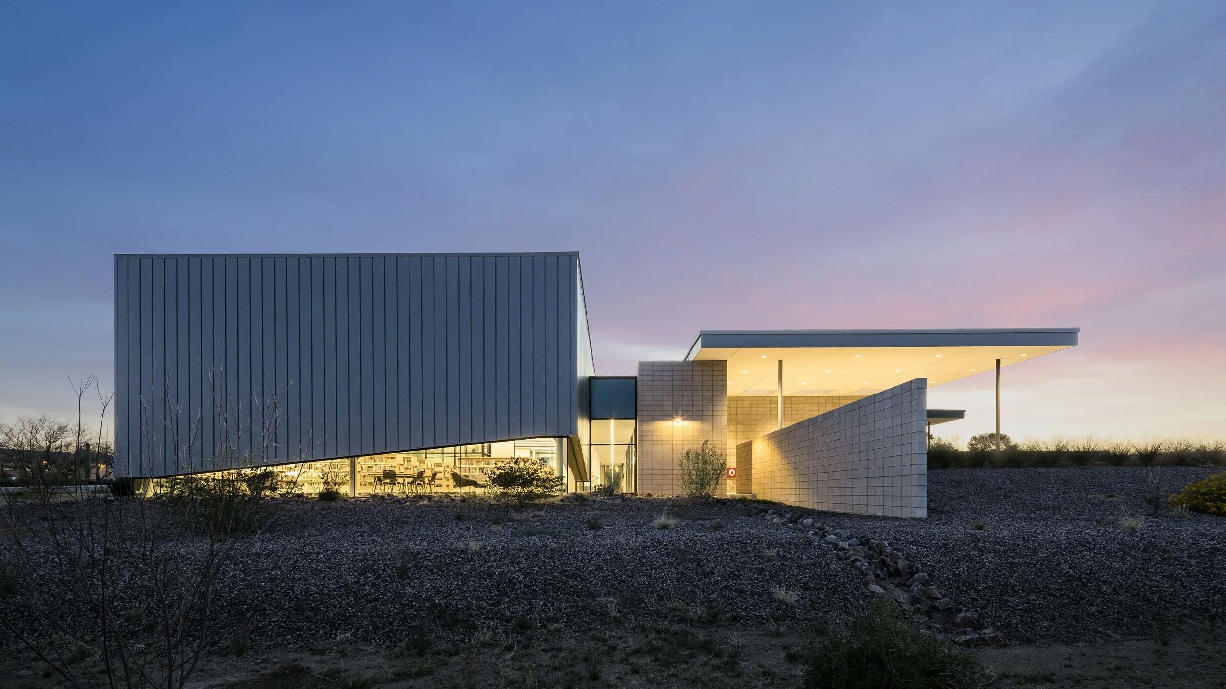 Exterior building view of Sahuarita Regional Library at dusk, with soft facility illumination that is oriented to minimize impact to the desert ecosystem at nighttime