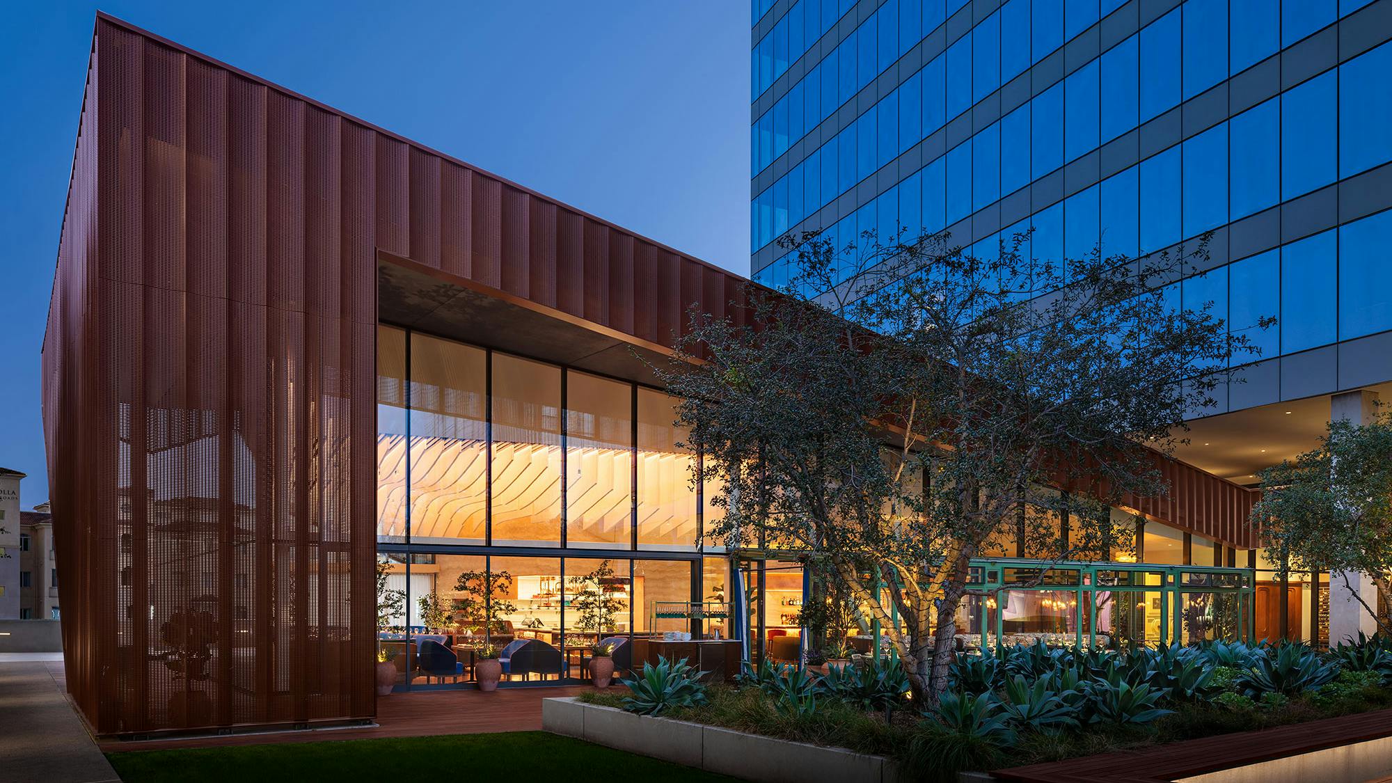 Exterior view shows Fleurette restaurant interior through expansive windows, with warm ambient lighting, intuitive movement paths, and cozy, intimate seating