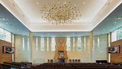 Contemporary synagogue space with clerestory windows and sculptural element overhead facing altar.