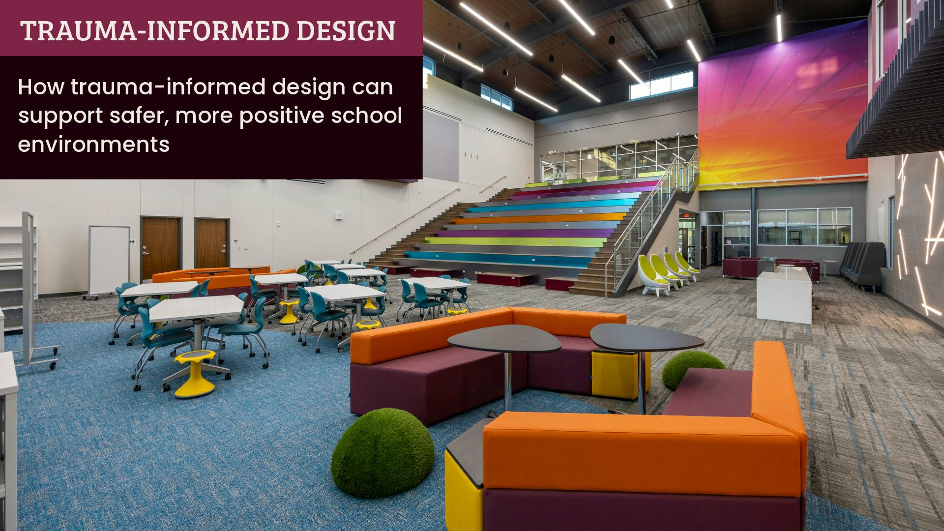 An elementary school library space designed with vivid sunset accent colors, modular furniture, linear lighting, and assembly stairs