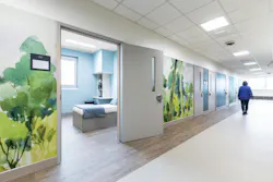 Custom murals printed on protective wall surfaces serve as a biophilic design element in a healthcare facility. Inspired by local landscapes, the watercolor-style imagery is rendered in soft tones found in nature, bringing a soothing respite from the stresses of behavioral health treatment.