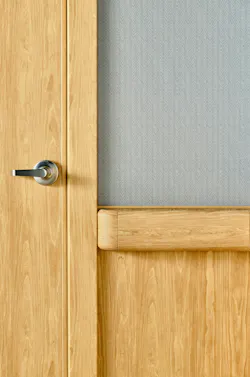 Close up detail of safety door, doorframe, and wall protection with rounded edges in light wood tones