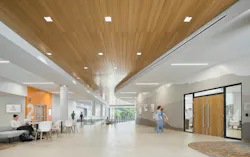 Open floor with stairway access, students sitting in a lounge area, and others walking toward a laboratory setting