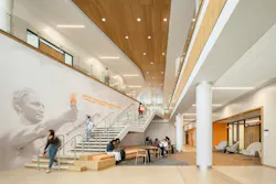 A generous stairway displays a wall graphic that reads: One that beareth a torch shadoweth oneself to give light to others.