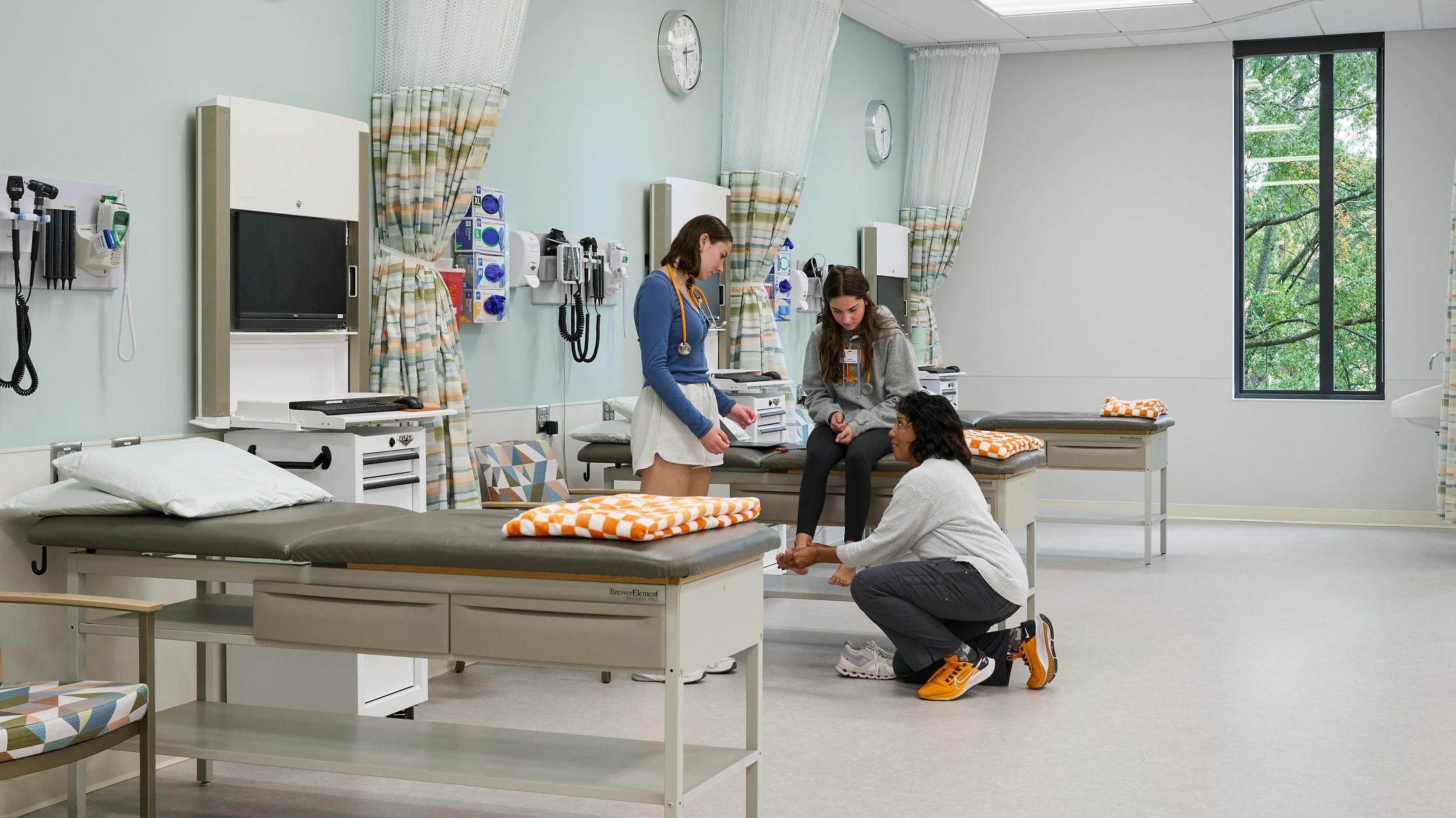 Nursing student and faculty perform a simulated patient exam on a volunteer in a realistic clinical environment