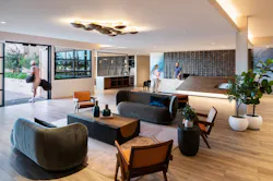 A spacious lobby welcomes residents and guests at The Monde, where the interior materials and color story begins with light neutrals, textured surfaces, comfortable seating, and natural materials.