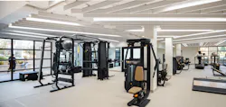 Fitness center with strength training equipment, cardio machines, comfortable lighting, and large windows to communal outdoor spaces