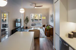 Residential unit with off white walls, neutral cabinetry and countertops, and wood floors