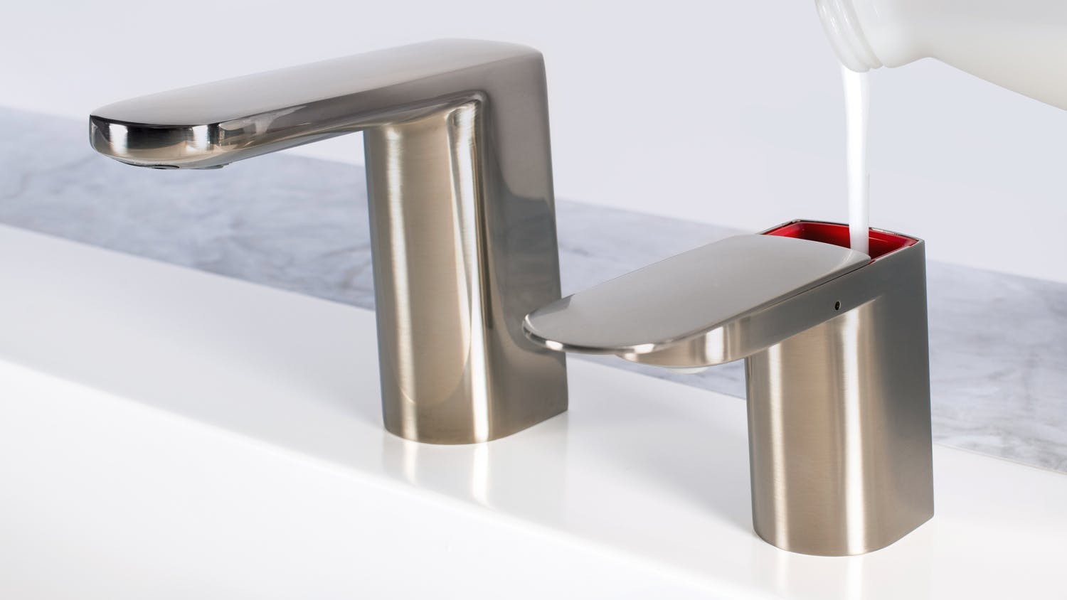 Brushed nickel finish washroom faucet and soap dispenser.