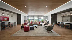 A large social space with layered lighting, daylight access, and multiple seating arrangements from a central lounge setup to counters with task chairs and individual soft seating.