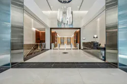 Long interior vestibule view to 99 Park Avenue lobby with marble reception desk, metal and glass surface accents