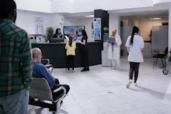 Hospital emergency room receptionist stands behind raised countertop, greeting multiple patients