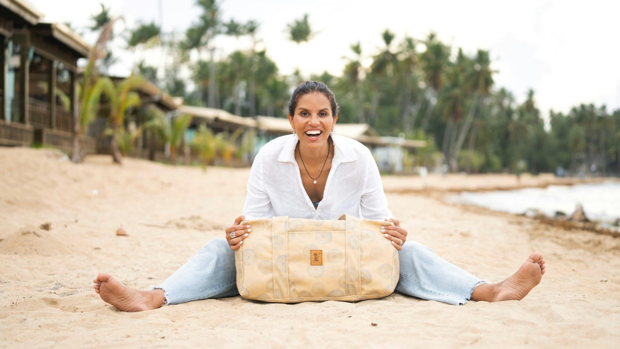 Joy Reyes, founder and CEO of New Hope Girls, sits on the beach with a bag made from Nassimi fabric.