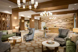 In the richly appointed lobby, variations in textile patterns and textures are complemented by sophisticated wood dividers, coordinating decorative tile, and a feature wall evoking the nearby hills.