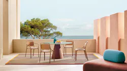 The Libre is a polypropylene, stackable armchair. It is shown in an outdoor setting around a table.