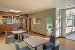 An open common area with wood finishes and a muted green, blue, gray, and sand color palette for surfaces and furnishings
