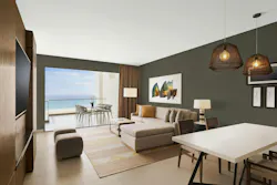 A hospitality rendering shows earthy Grounded walls paired with textured neutral fabrics, carpeting, pendant lighting, and wood furnishings