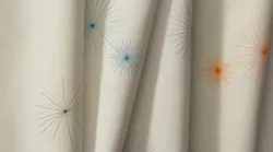 Aperture Embroider textile features finely stitched radial bursts across an open ground. Shown with black, blue, and orange bursts.