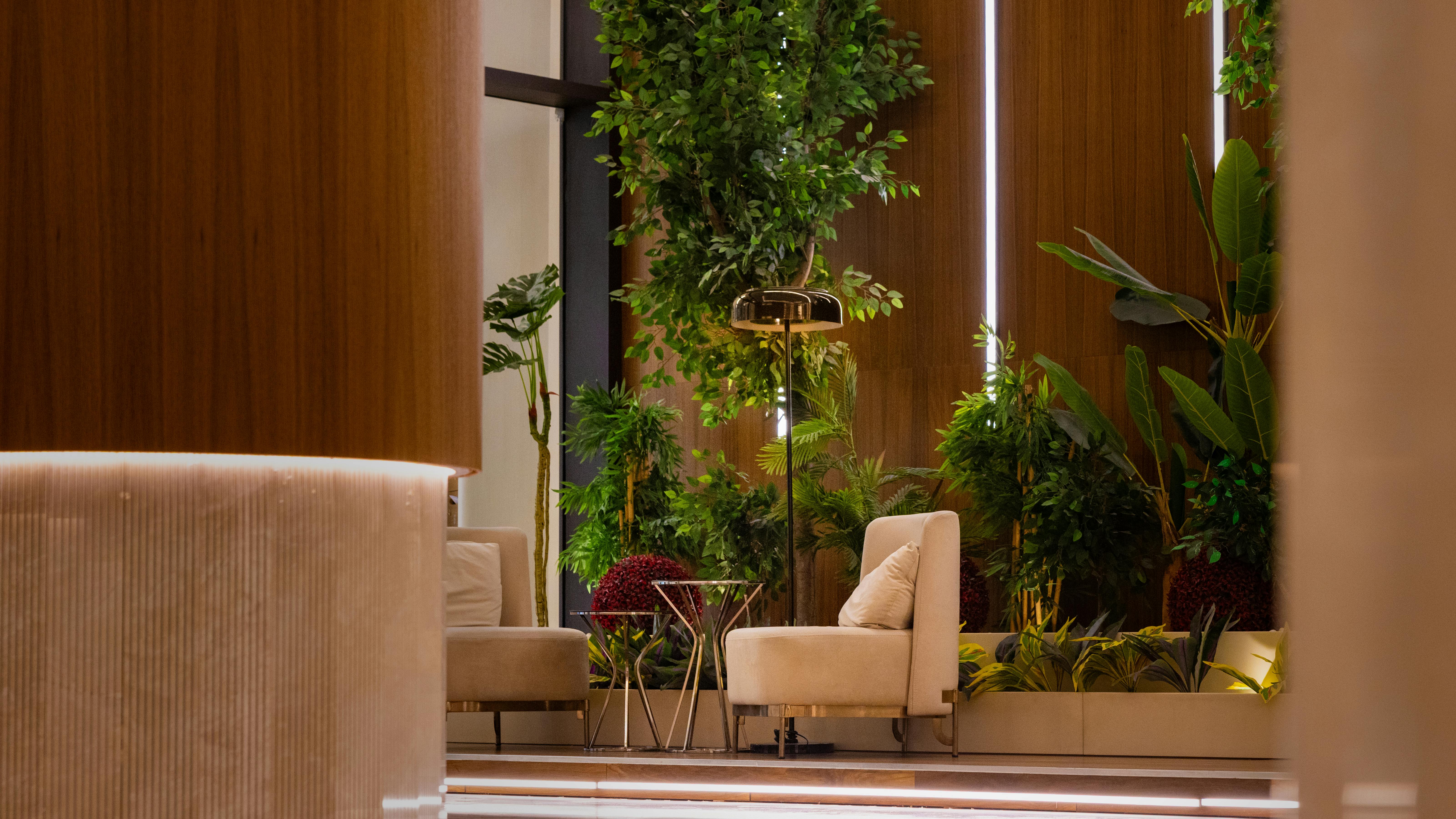Lounge seating in boutique hotel with wood paneling and large plants in background.