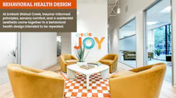 Open lounge area with Create Joy wall sign, golden yellow barrel chairs, and and orange and white checkered area rug