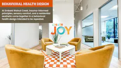 Open lounge area with Create Joy wall sign, golden yellow barrel chairs, and and orange and white checkered area rug