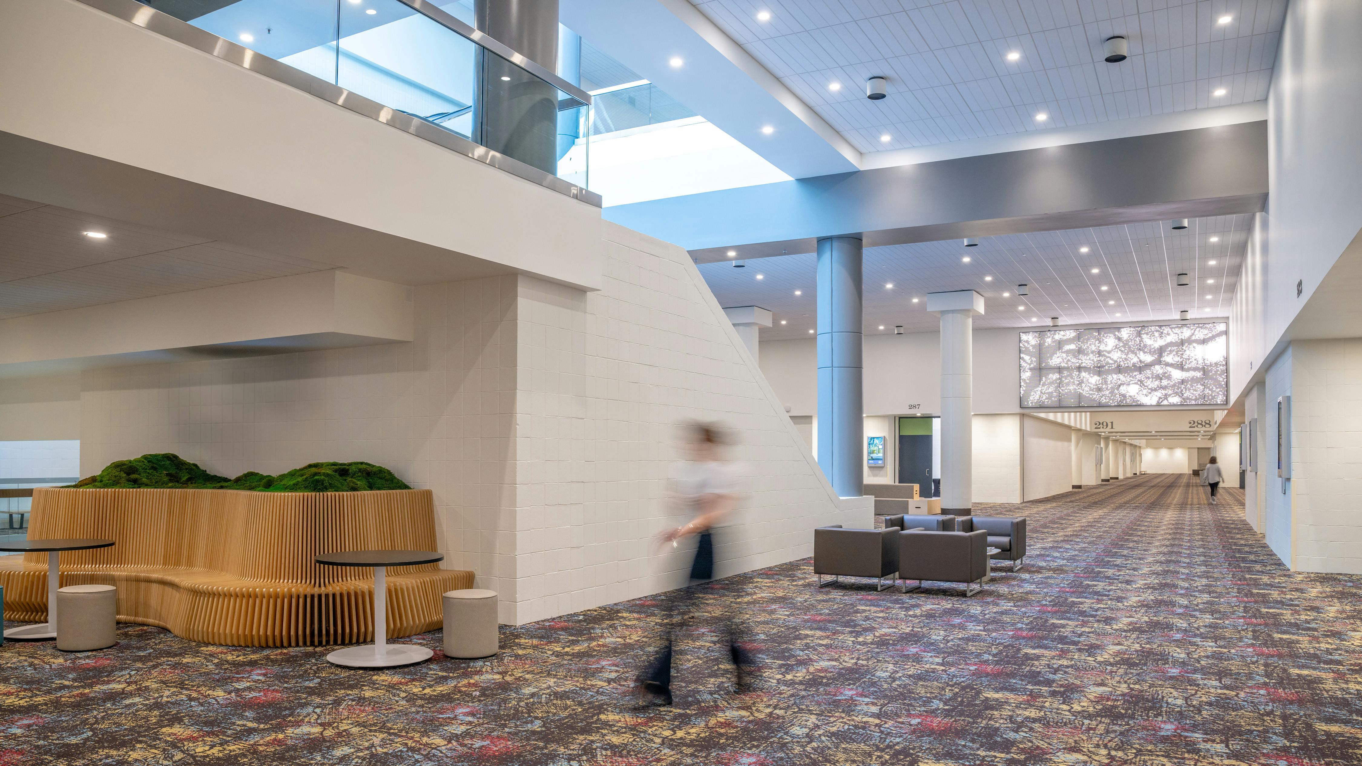 A long interior view of convention center shows updated lighting, carpet, and informal seating zones