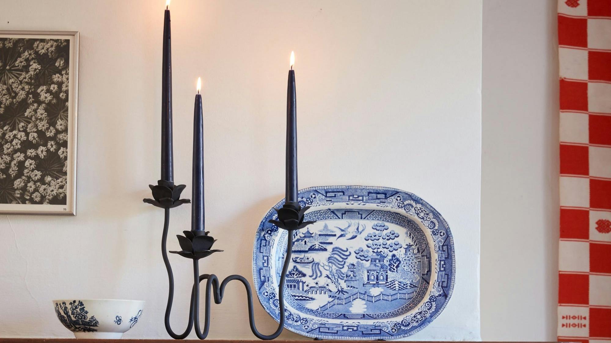 A closeup of the candelabra with three black candles lit on top.