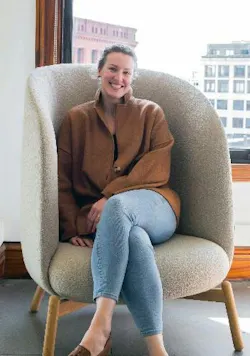 Portrait of Natalie Hartkopf sitting in high-backed lounge chair.