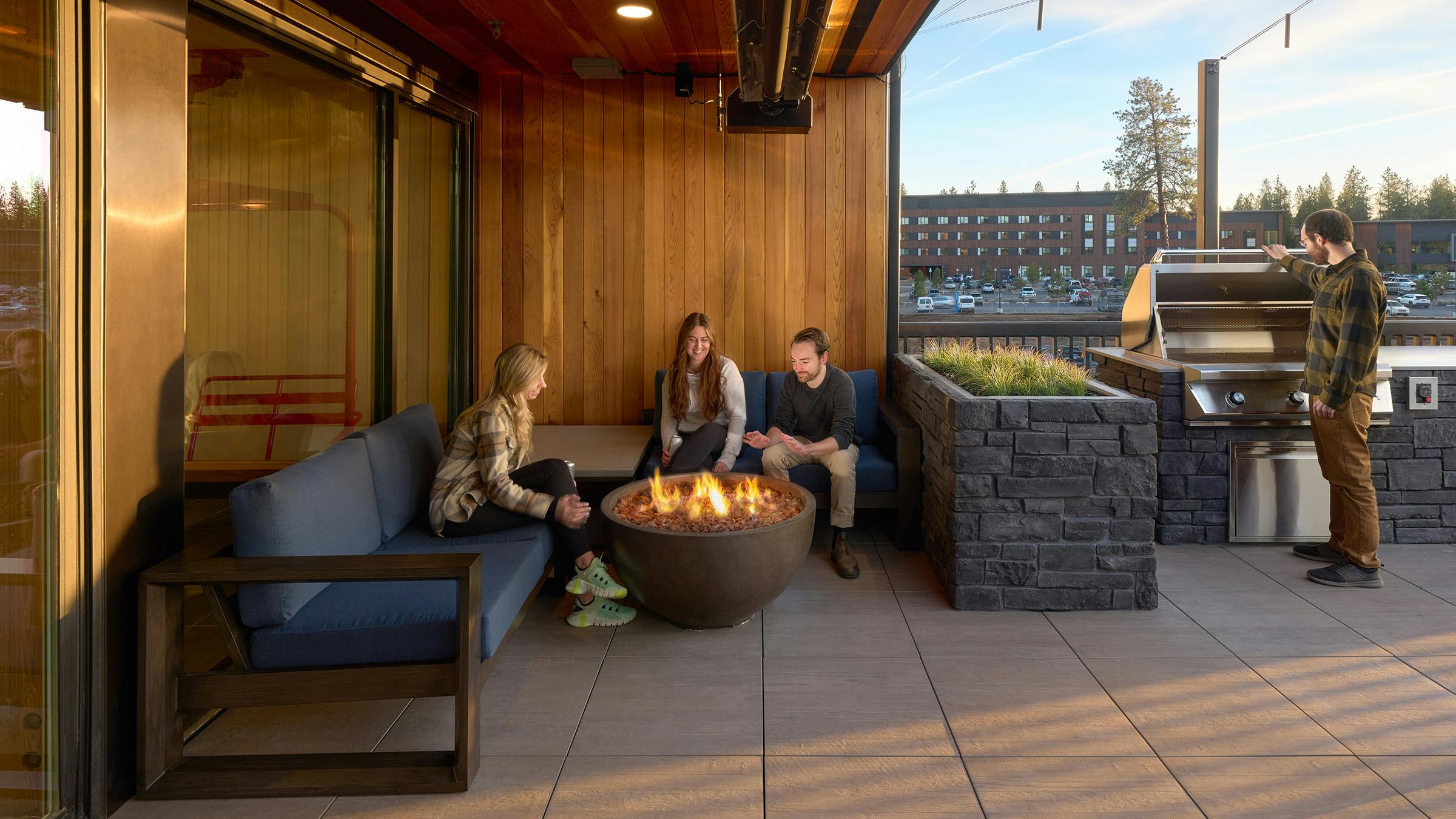 Residents sitting at an outdoor patio with built-in grill and sunshade